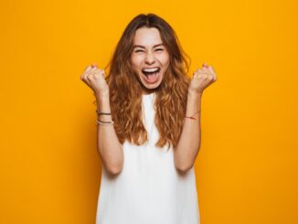 Portrait of a happy young girl screaming celebrating isolated over yellow background. old crap