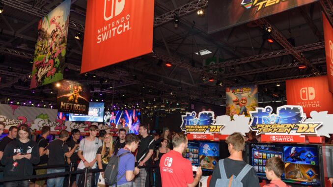 People playing games under a Nintendo Switch banner at E3