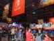 People playing games under a Nintendo Switch banner at E3