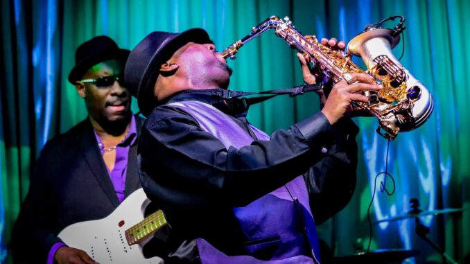 A man playing guitar and another on saxaphone in a funk band similar to those available in Far Cry 6