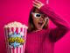 beautiful girl watching movie using 3d glasses eating box with popcorns surprised with hand on head after seeing movie blooper
