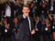 Ethan Hawke, in a suit, pointing at the camera with a crowd behind him