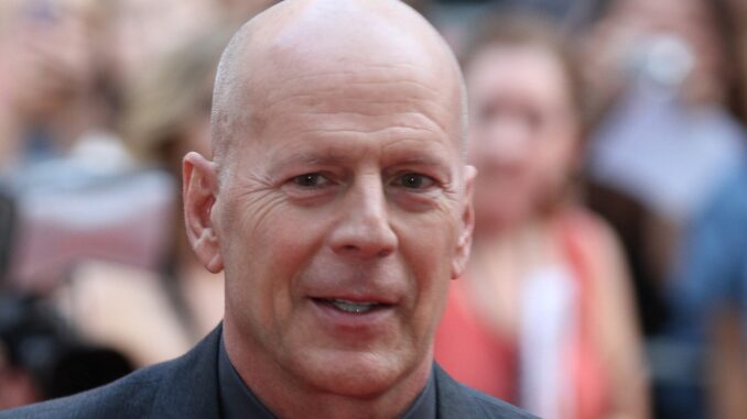 A headshot of Bruce Willis with a blurred crowd behind him, possibly after having made a terrible action movie