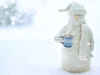 the snowman, holding a mug of hot chocolate with a blurred white snowy background