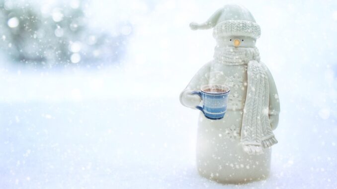 the snowman, holding a mug of hot chocolate with a blurred white snowy background