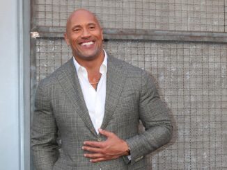 Dwayne Johnson in a grey jacket leaning against a wall. Vin Diesel and The Rock