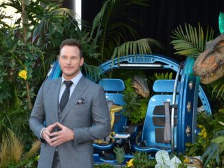 Chris Pratt voice standing in front of a set from Jurassic world