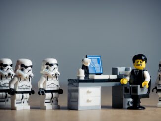 SEveral Lego stormtroopers surround a legoman at a desk. New Lego Star Wars Game