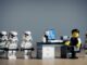 SEveral Lego stormtroopers surround a legoman at a desk. New Lego Star Wars Game