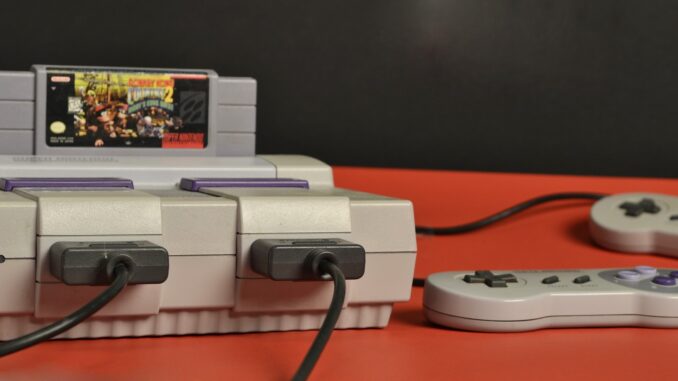 a snes system with two controllers on a red table. SNES Maxi.