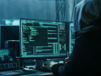 hacker cage sits in dark room starring at code on a monitor