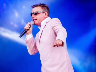 Suggs on stage in pink jacket multiverse of madness