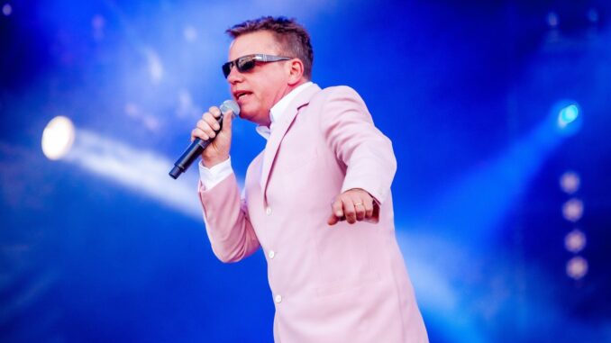 Suggs on stage in pink jacket multiverse of madness