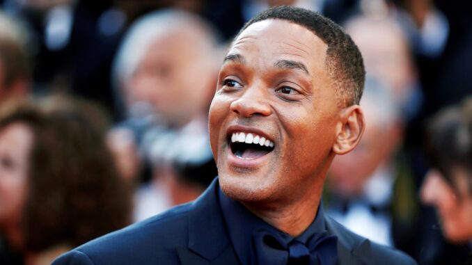 will smith slap looking happy in front of a crowd. Shot from shoulders up