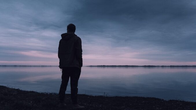 lonely man Not seen Top Gun: Maverick looks out over sea at dusk