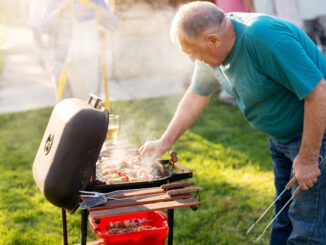 Elderly man is rotating meat and vegetable on a stick that is being grilled on the vintage grill. ferris bueller spin-off