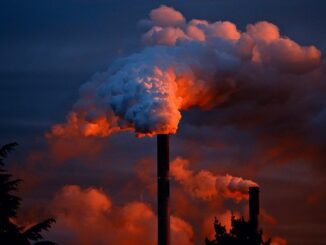 a smokestack at sunset belching out fumes. Industrial planet