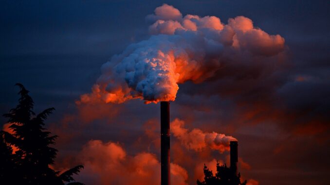 a smokestack at sunset belching out fumes. Industrial planet