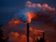 a smokestack at sunset belching out fumes. Industrial planet