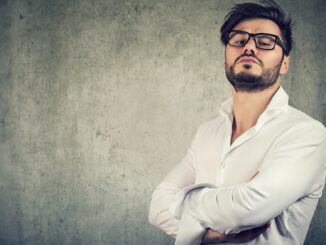 a pompous looking man in glasses aginst a white wall. Not enjoying the rings of power