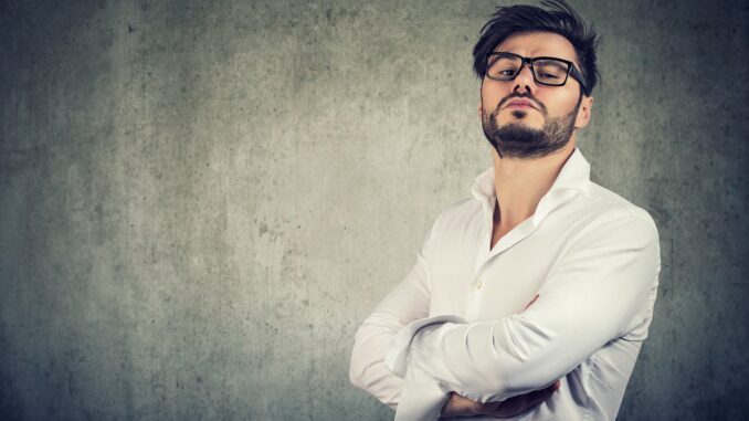 a pompous looking man in glasses aginst a white wall. Not enjoying the rings of power