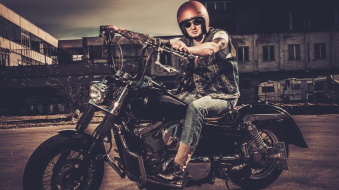 Tattooed biker and his bobber style motorcycle on a city streets. Easy Rider reboot