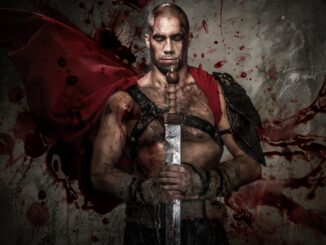 Wounded gladiator holding sword covered in blood with both hands. Gladiator sequel