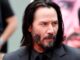 Keanu Reeves. Black jacket, shirt and tie, headshot. Beard. Long Hair. John Wick Shooting