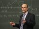 a bald professor in front of a blackboard explaining something . lady ghostbusters