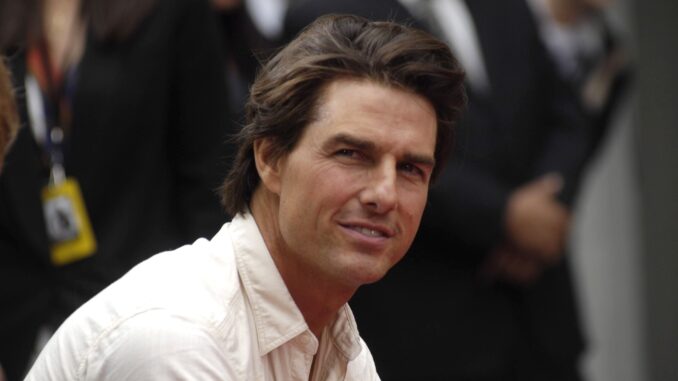 Tom Cruise wearing open coller white shirt from side. Top Gun Maverick Iran.