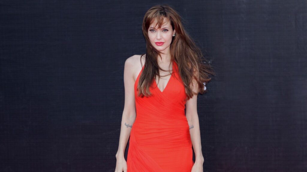angelia jolie in red dress against black background