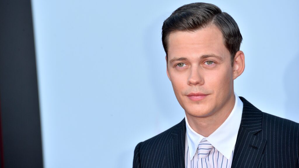 bill skarsgard, headshot against blue background