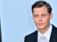 bill skarsgard, headshot against blue background