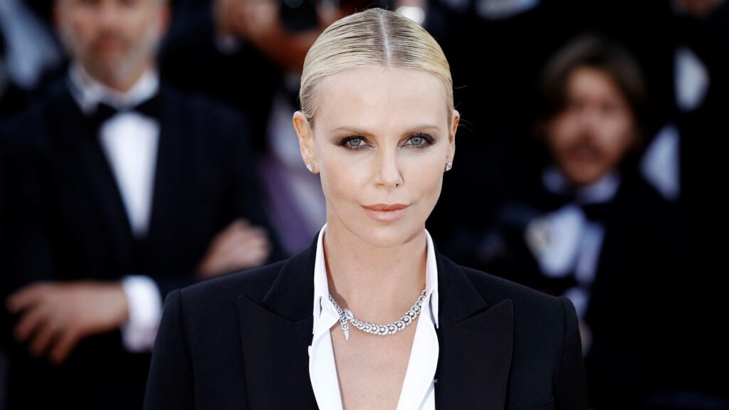 Charlize Theron from shoulders up with crowd behind her