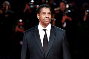 Denzel Washington in black suit with crowd behind him