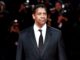 Denzel Washington in black suit with crowd behind him