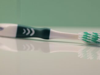 a green toothbrush on it's side on a white surface